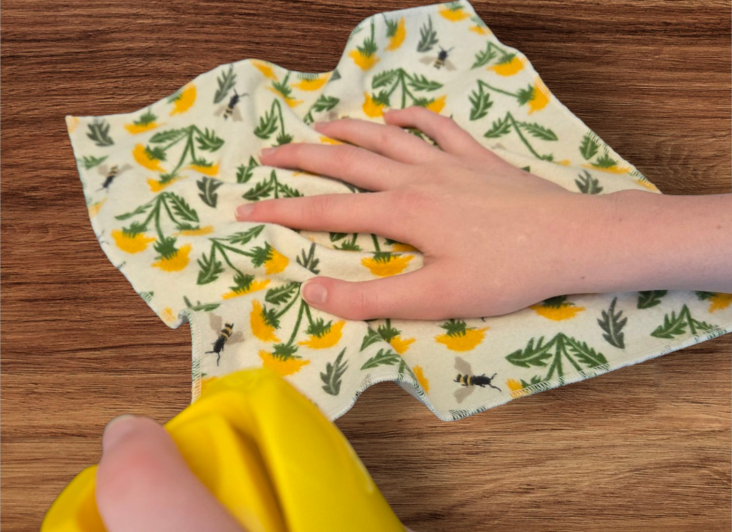 Flannel cloth dusting wood surface Flannel cloth, yellow flowers and bees on cloth. Picture is showing how product is used to dust a wood surface.